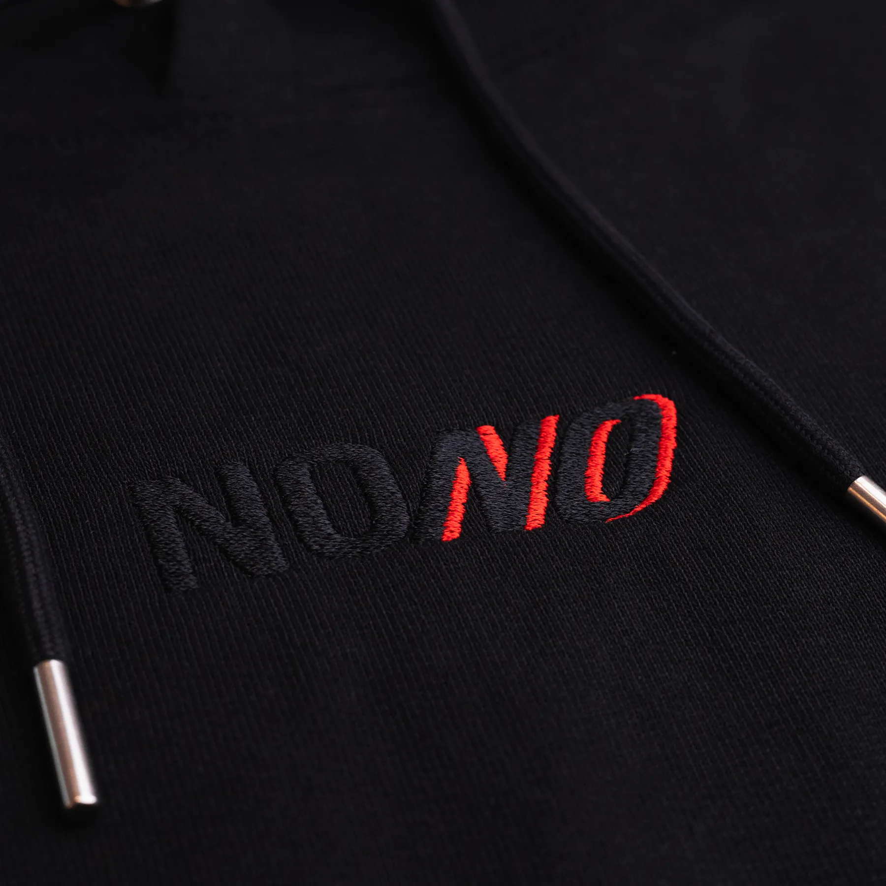 Close-up of the tone-on-tone NONO embroidery with the red italic second NO